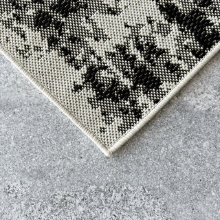 Close-up of a textured rug with a geometric pattern on a concrete floor.