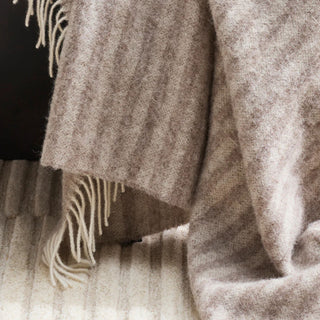 Close-up of a textured throw with fringes on a dark background