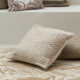 Textured beige pillow on a patterned surface with neutral-toned pillows in the background.