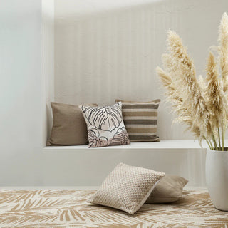 Decorative pillows on a bench with a vase of pampas grass in a minimalistic room.