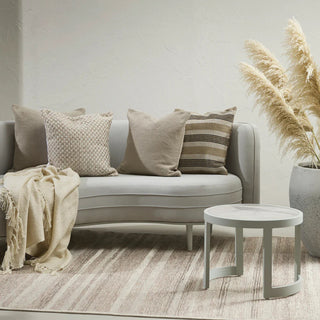 Gray sofa with decorative pillows and a small table in a living room setting.