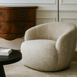 Beige armchair in a room with wooden furniture and a lamp.