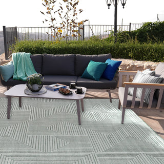 Outdoor patio with gray sofa, coffee table, and rug on a sunny day.