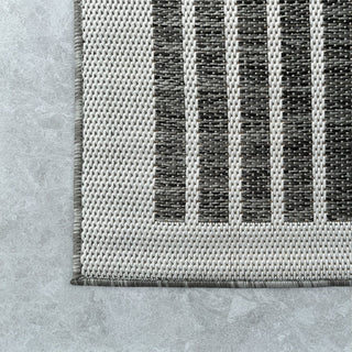 Textured rug with black and gray stripes on a concrete floor