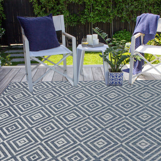 Outdoor setting with chairs, table, and patterned rug on a patio.