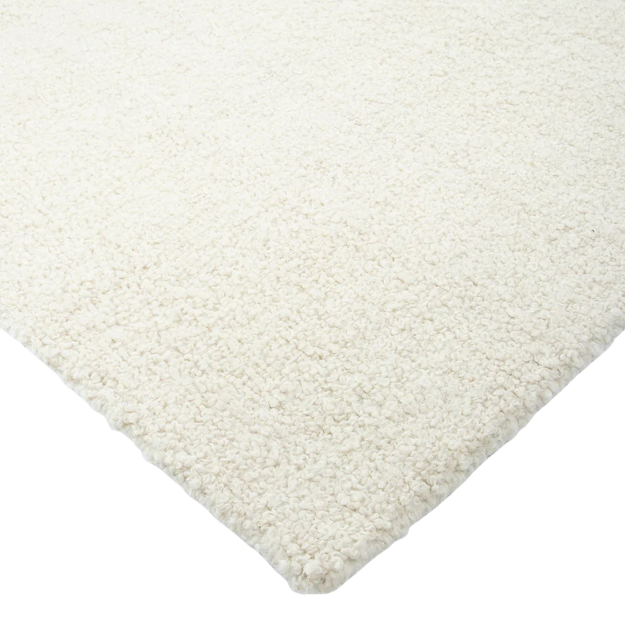 Close-up of a textured white rug corner on a white background