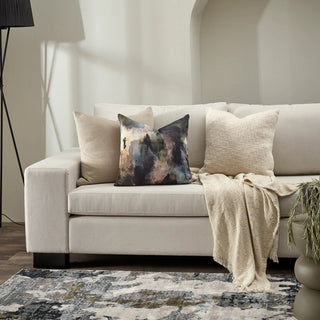 Beige sofa with decorative pillows and a blanket in a living room setting