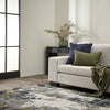 Modern living room with a beige sofa, decorative pillows, and a patterned rug.