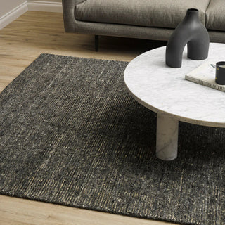 Living room with a dark textured rug, gray sofa, and marble coffee table.