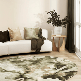 Living room with a white sofa, decorative pillows, a round green rug, and a plant.