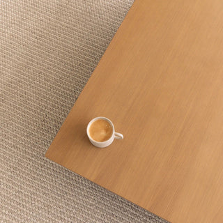White coffee cup on a wooden surface with a textured beige carpet background