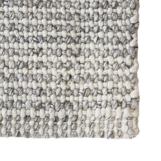Close-up of a textured woven rug with a neutral color palette.