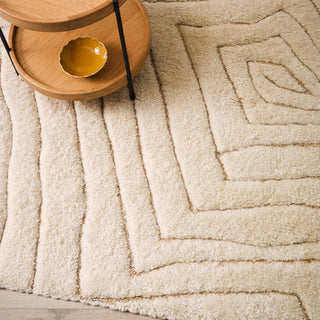 Beige textured rug with geometric pattern, wooden side table, and yellow bowl.