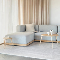 Modern living room with a light gray sectional sofa, wooden coffee table, and decorative items.
