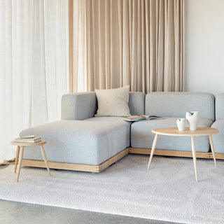 Modern living room with a light gray sectional sofa, wooden coffee table, and decorative items.