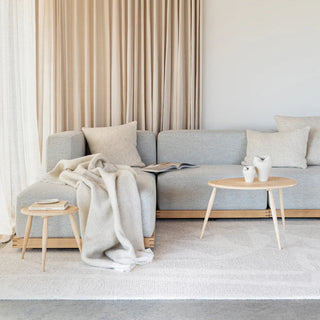 Gray sofa with a blanket and small table in a minimalistic living room.