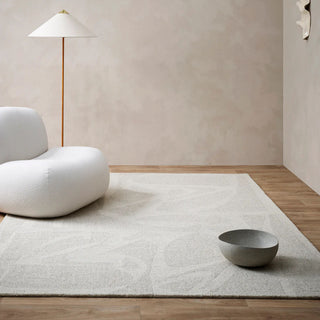 Modern living room with a white rug, gray bowl, and white chair.