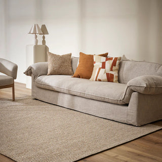 Gray sofa with patterned cushions in a living room setting on a grey and beige rug
