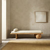 Minimalist wooden bench with cushion against a plain wall.