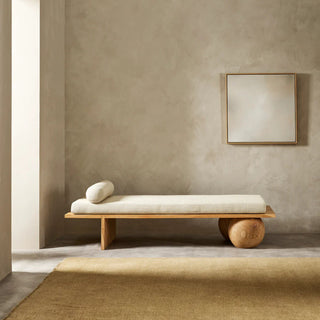 Minimalist wooden bench with cushion against a plain wall.