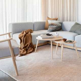 Modern living room with a gray sofa, wooden armchair, and coffee tables.