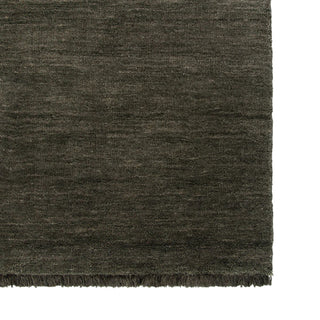 Dark gray textured rug with fringes on a white background