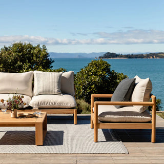 Outdoor furniture set with cushions on a deck overlooking a body of water.
