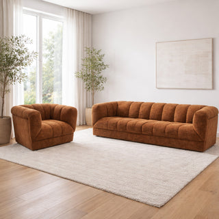 Brown sofa and armchair in a bright living room with large windows and plants.