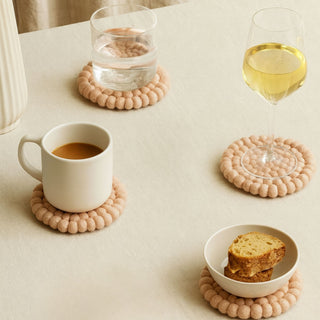 Blush pink felt ball coasters – handmade in NZ for a chic, practical table accent.