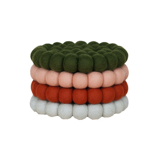 Set of four felt ball coasters in green, blush pink, rust, and light grey, handcrafted from 100% New Zealand wool.