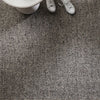 Close-up of a textured gray carpet with white shoes and a white object in the corner.