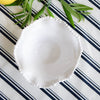 White melamine pearl bowl overhead view on striped tablecloth with greenery