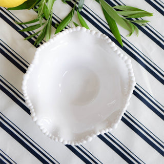 White melamine pearl bowl overhead view on striped tablecloth with greenery